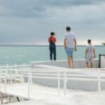 Water Features - Three People Standing on White Surface Near Body of Water