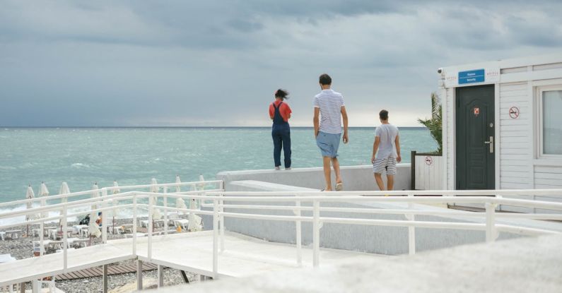 Water Features - Three People Standing on White Surface Near Body of Water