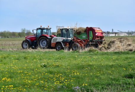 Soil Preparation - a red tractor pulling a trailer of hay through a field