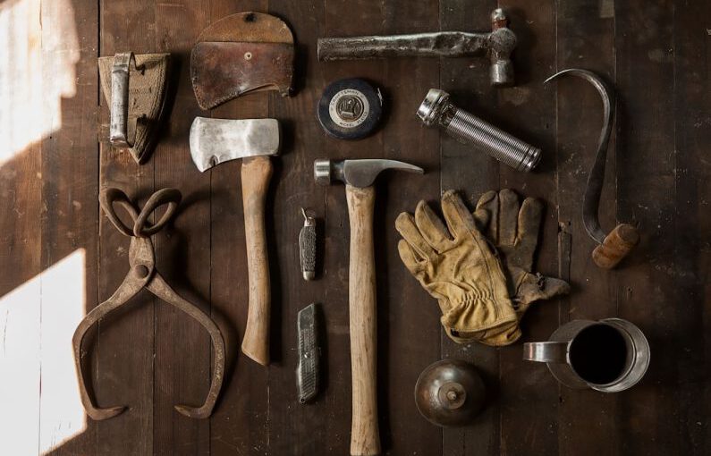 Hand Tools - clothes iron, hammer, axe, flashlight and pitcher on brown wooden table