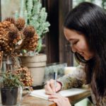 Garden Planning - Happy young ethnic woman writing article in cozy workplace