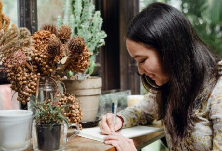 Garden Planning - Happy young ethnic woman writing article in cozy workplace