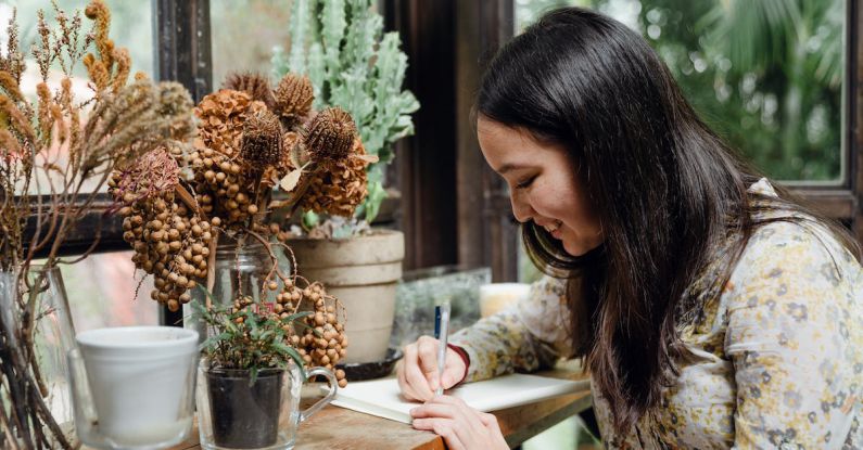 Garden Planning - Happy young ethnic woman writing article in cozy workplace