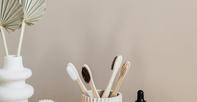 Organic Alternatives - Collection of bamboo toothbrushes and organic natural soaps with wooden body brush arranged with recyclable glass bottle with natural oil and ceramic vase with artificial plant